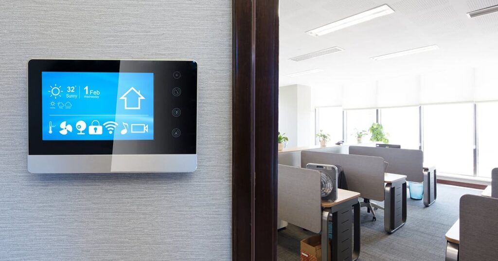 LCD control panel on the wall with a living area in the background to the right