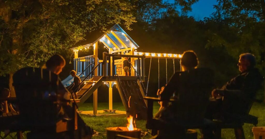 Backyard at night with a lit up child slide and play station