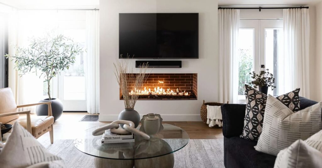 Living area with white walls, a couch and lounge chair with a flat screen TV on the wall above a fireplace