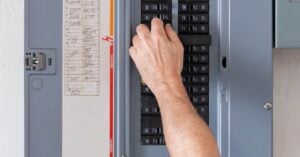 Person adjusting switches on a surge protector fuse box