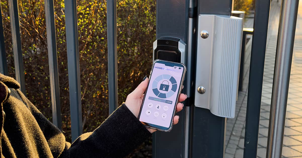 Person standing by a metal gate looking at a smart phone with a lock screen on it