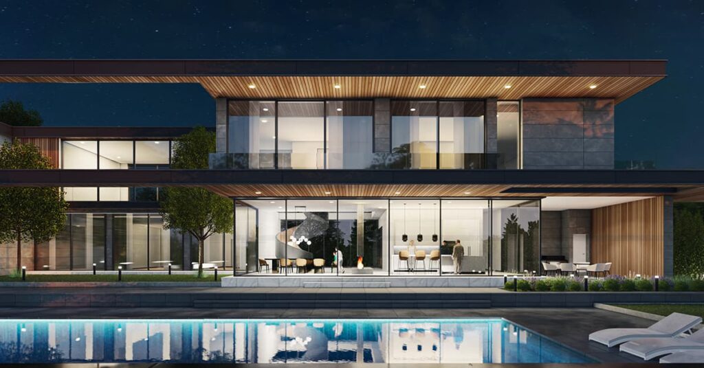 Outdoor view of a modern home at night with many glass walls and a pool in the foreground