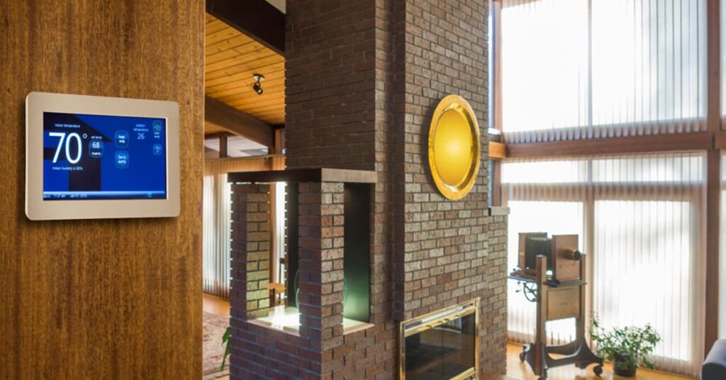 Home interior with a smart home control screen on the wall and a brick fireplace in the middle of the room to the right