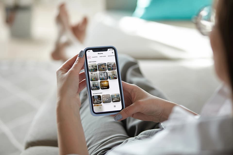 Person with eyeglasses sitting and looking at a smart phone with several images of security videos on it