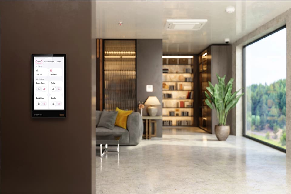 Interior room with bookcase in background with couch and window including a flat screen control panel on the wall controlling shades and security