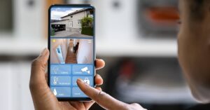 Person looking at a smart phone with security camera feeds and security apps on the screen