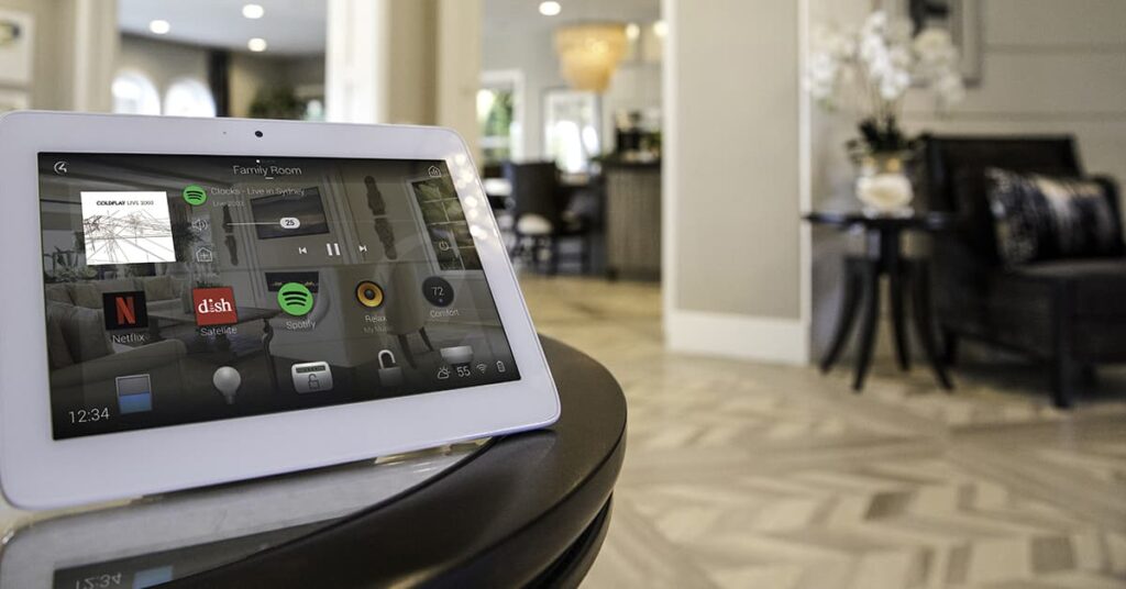 Tablet PC on a table with apps on the screen and a living area in the background