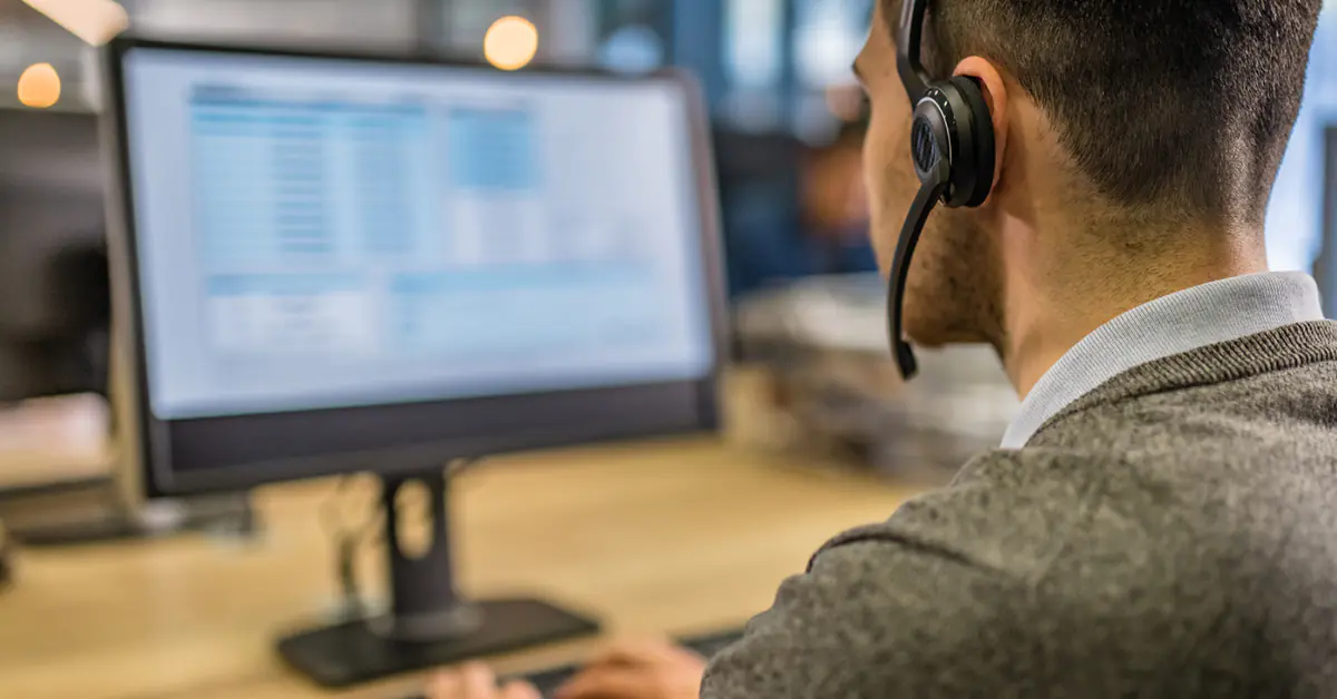 Support person with a headset on looking at a monitor