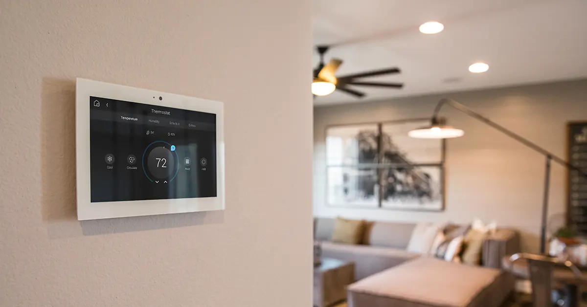 Control panel on the wall with a living area with ceiling fan in the background